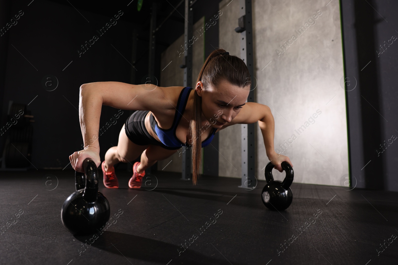 Photo of Sportswoman doing kettlebell push up during crossfit workout in gym