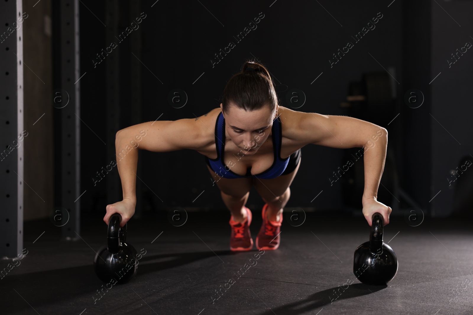 Photo of Sportswoman doing kettlebell push up during crossfit workout in gym