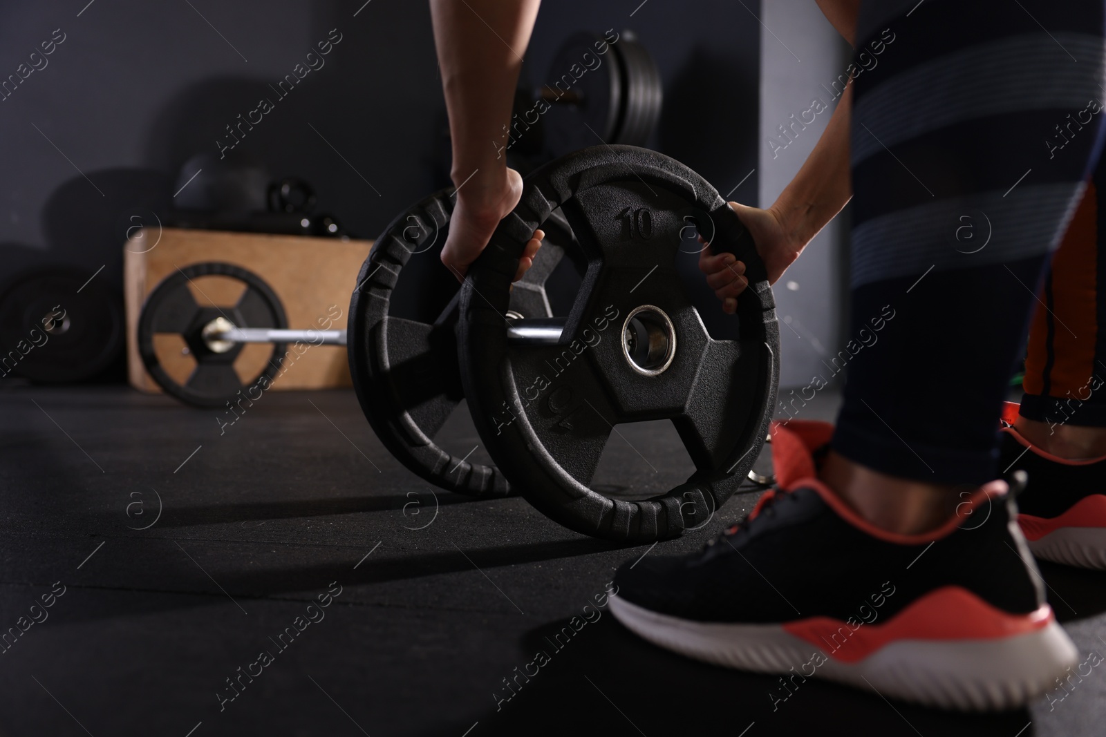 Photo of Sportswoman with barbell during crossfit workout in gym, closeup