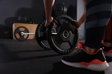 Photo of Sportswoman with barbell during crossfit workout in gym, closeup