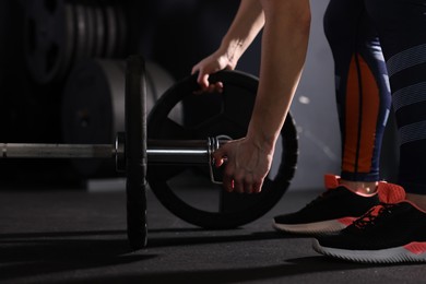 Photo of Sportswoman with barbell during crossfit workout in gym, closeup