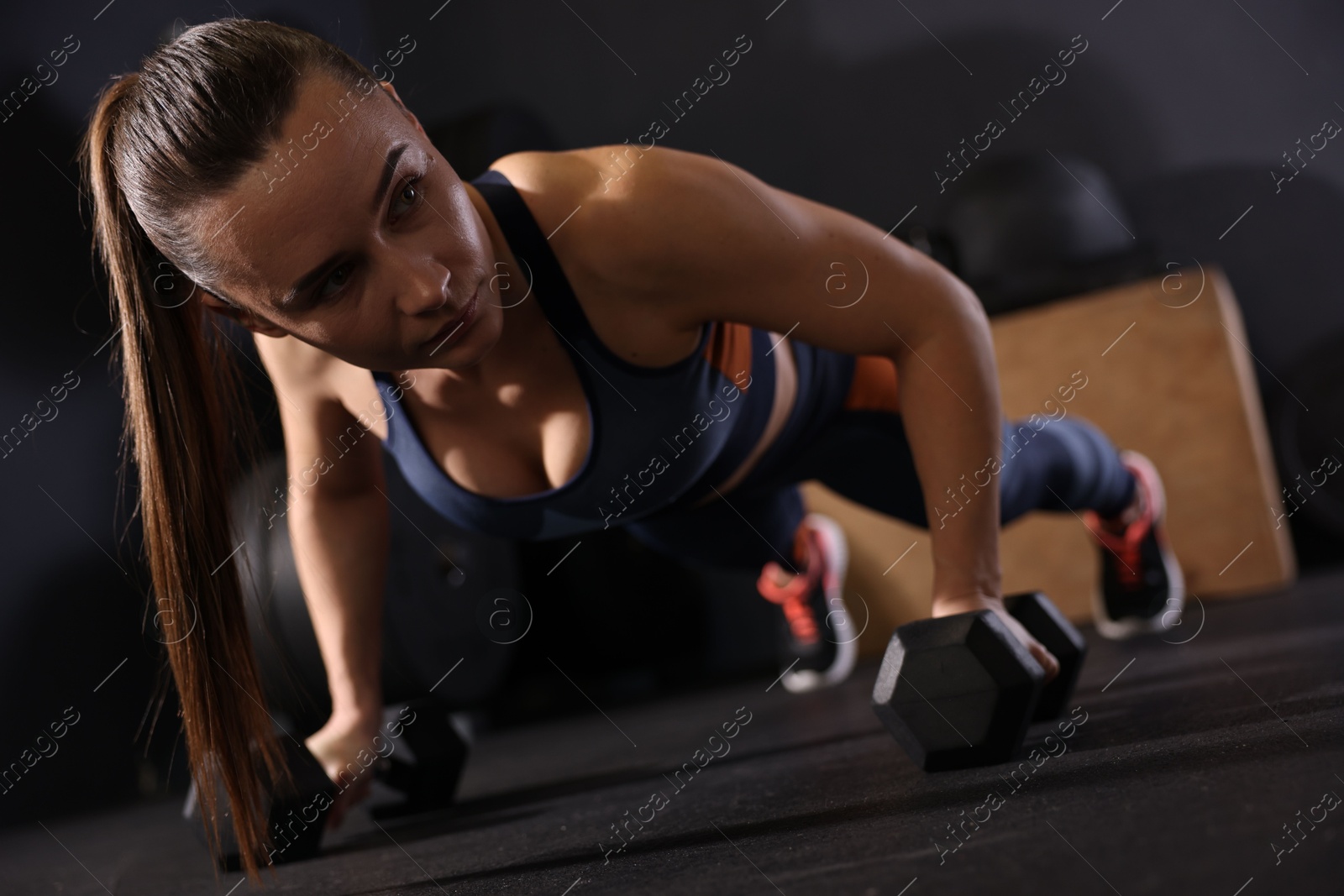 Photo of Sportswoman doing dumbbell push up during crossfit workout in gym