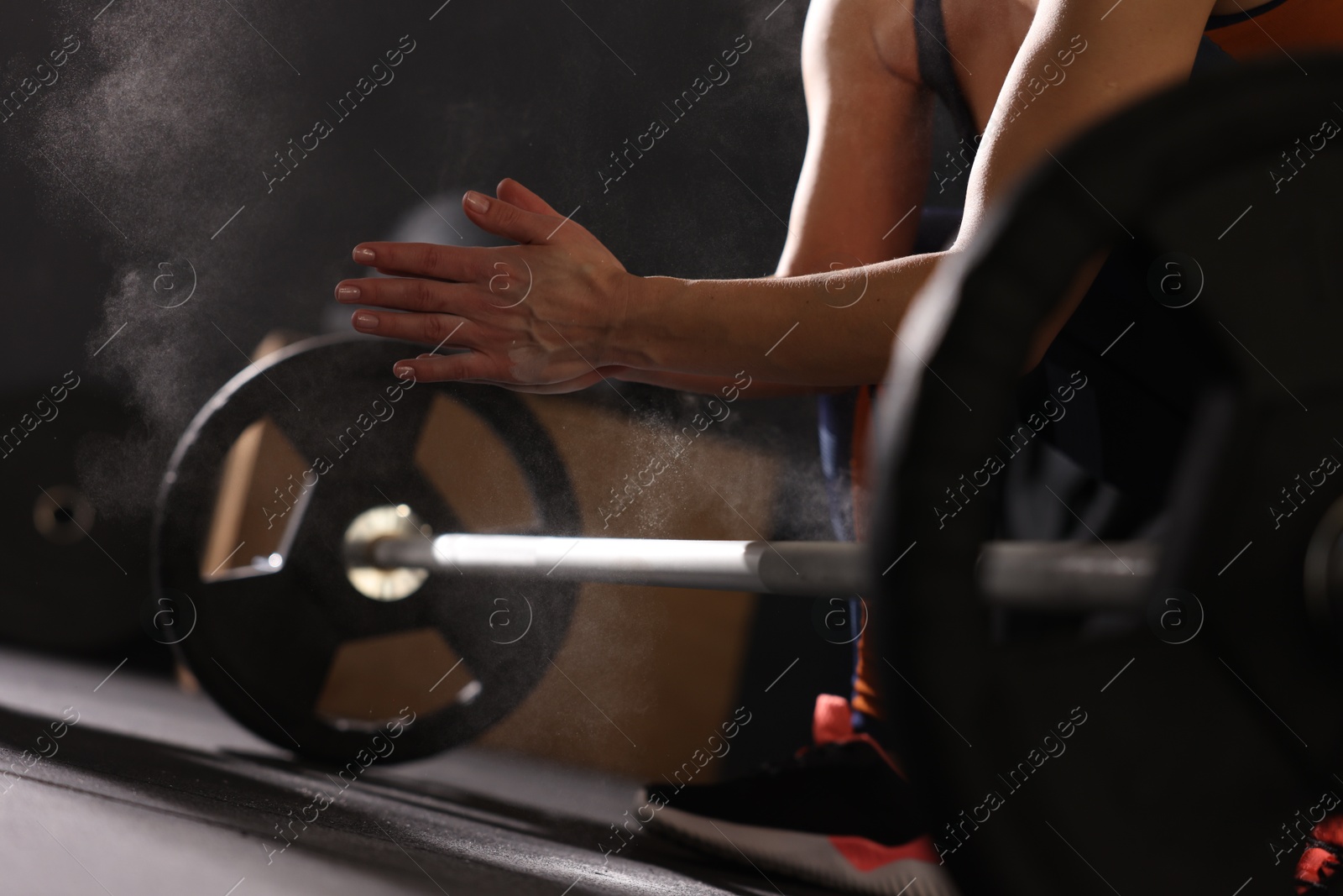 Photo of Sportswoman with barbell during crossfit workout in gym, closeup