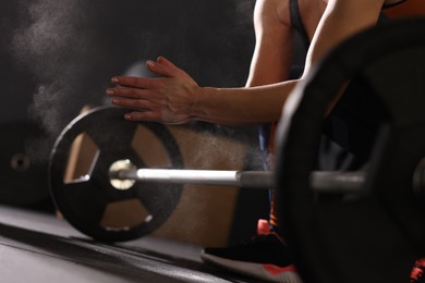 Photo of Sportswoman with barbell during crossfit workout in gym, closeup