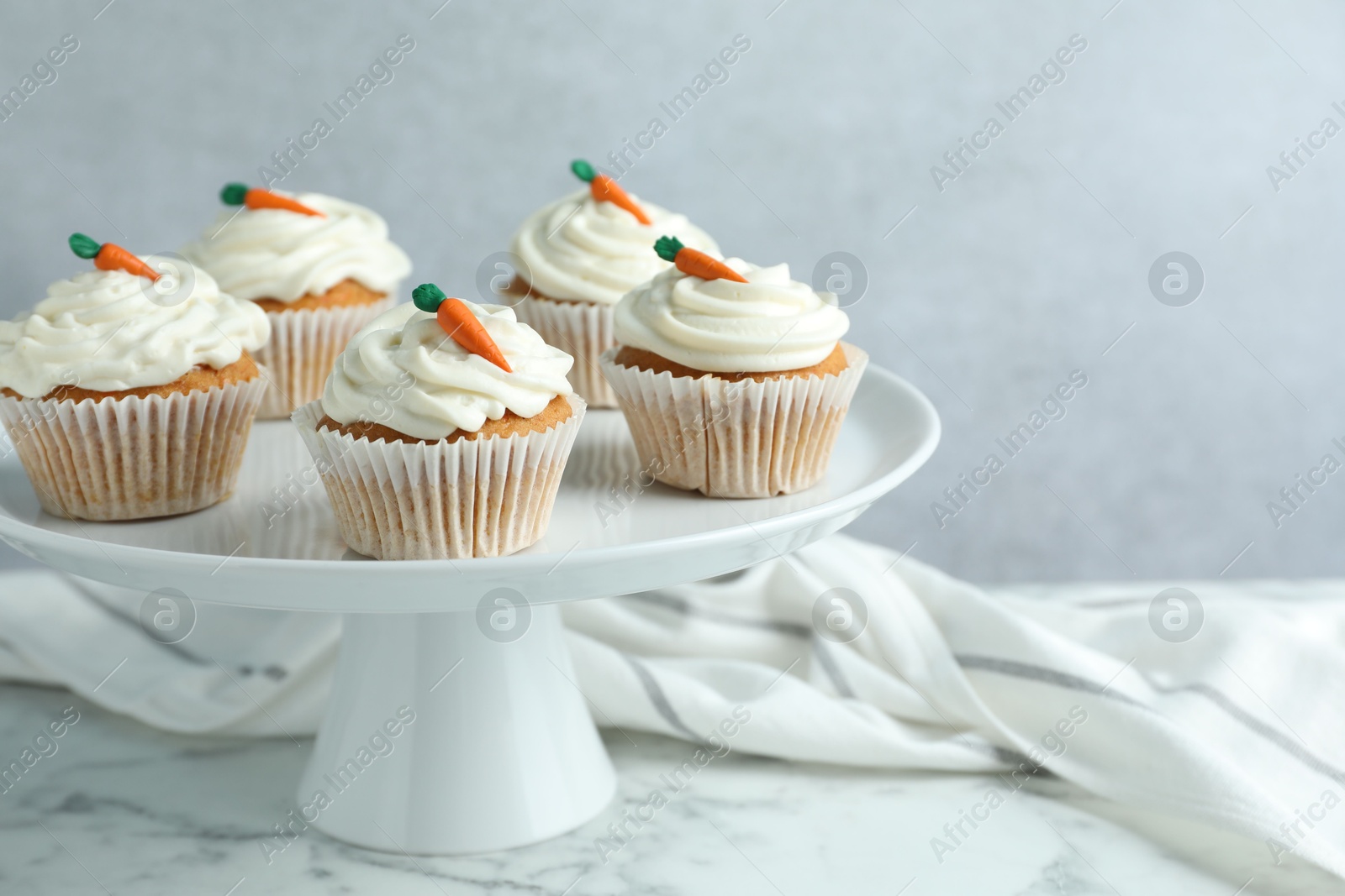 Photo of Delicious carrot cupcakes on white marble table against grey background, closeup