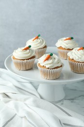 Photo of Delicious carrot cupcakes on white marble table against grey background