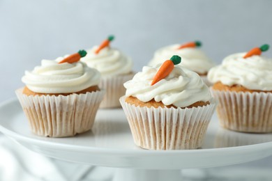 Photo of Delicious carrot cupcakes on stand against grey background, closeup