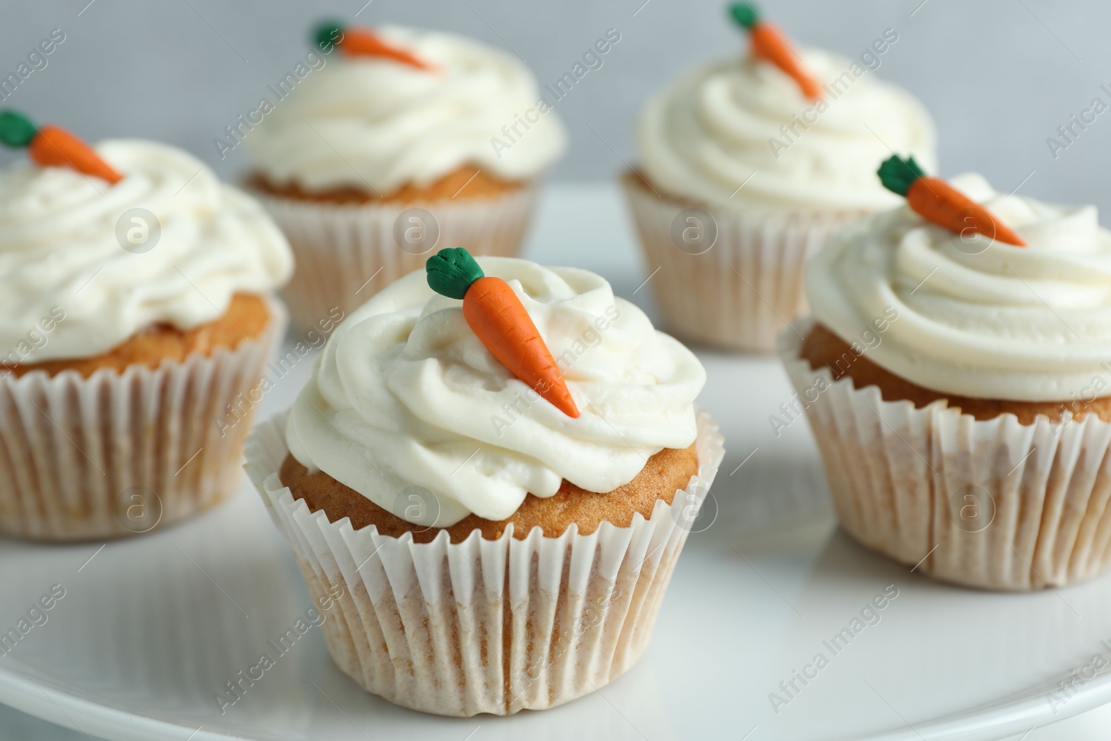 Photo of Delicious carrot cupcakes on plate against grey background, closeup