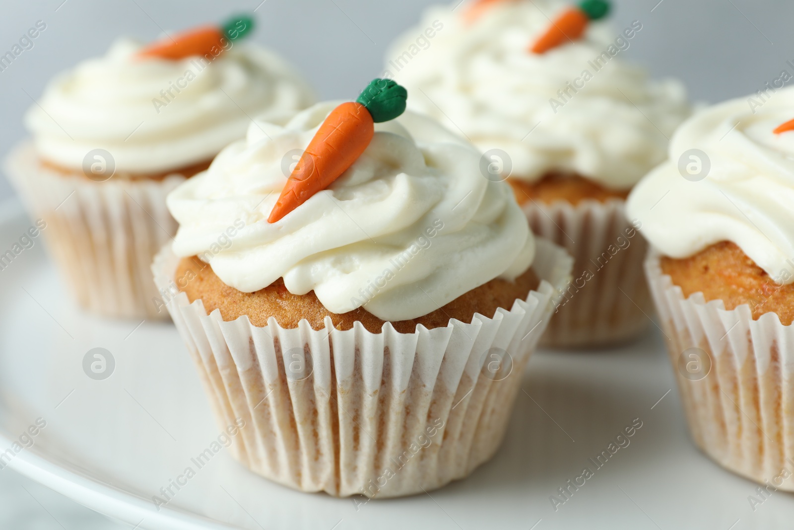 Photo of Delicious carrot cupcakes on plate against grey background, closeup