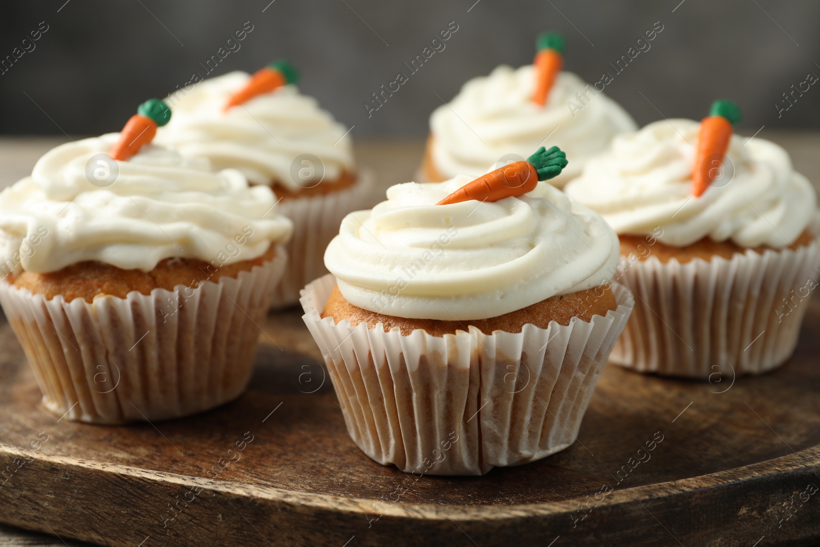 Photo of Delicious carrot cupcakes on wooden board, closeup