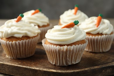 Photo of Delicious carrot cupcakes on wooden board, closeup