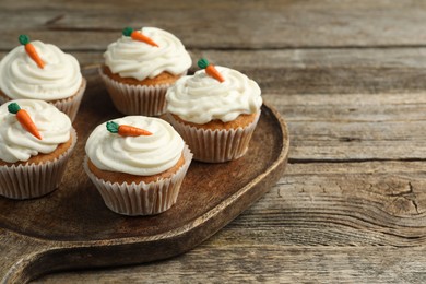 Photo of Delicious carrot cupcakes on wooden table, closeup. Space for text