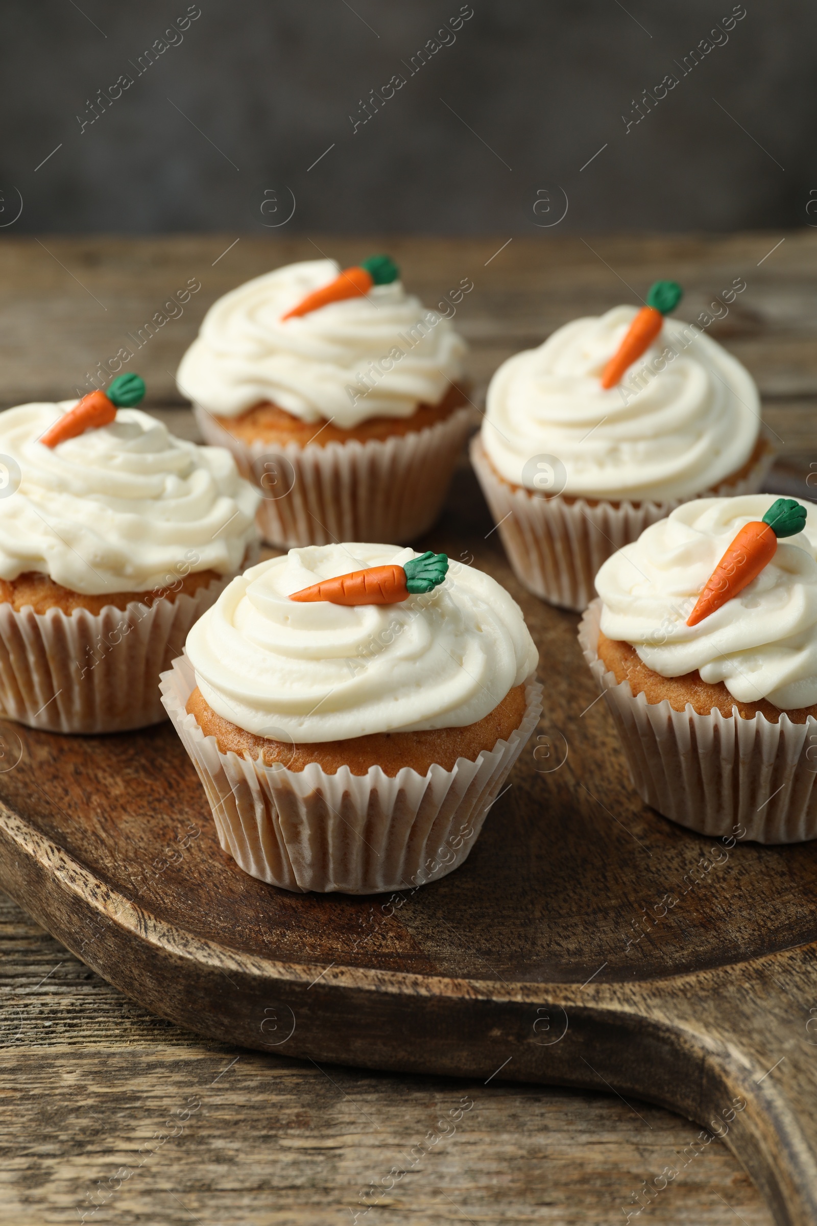 Photo of Delicious carrot cupcakes on wooden table against grey background, closeup