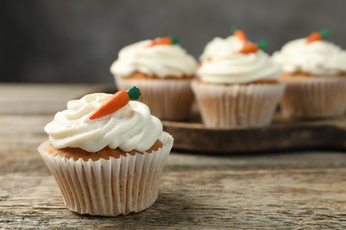 Photo of Delicious carrot cupcakes on wooden table, closeup