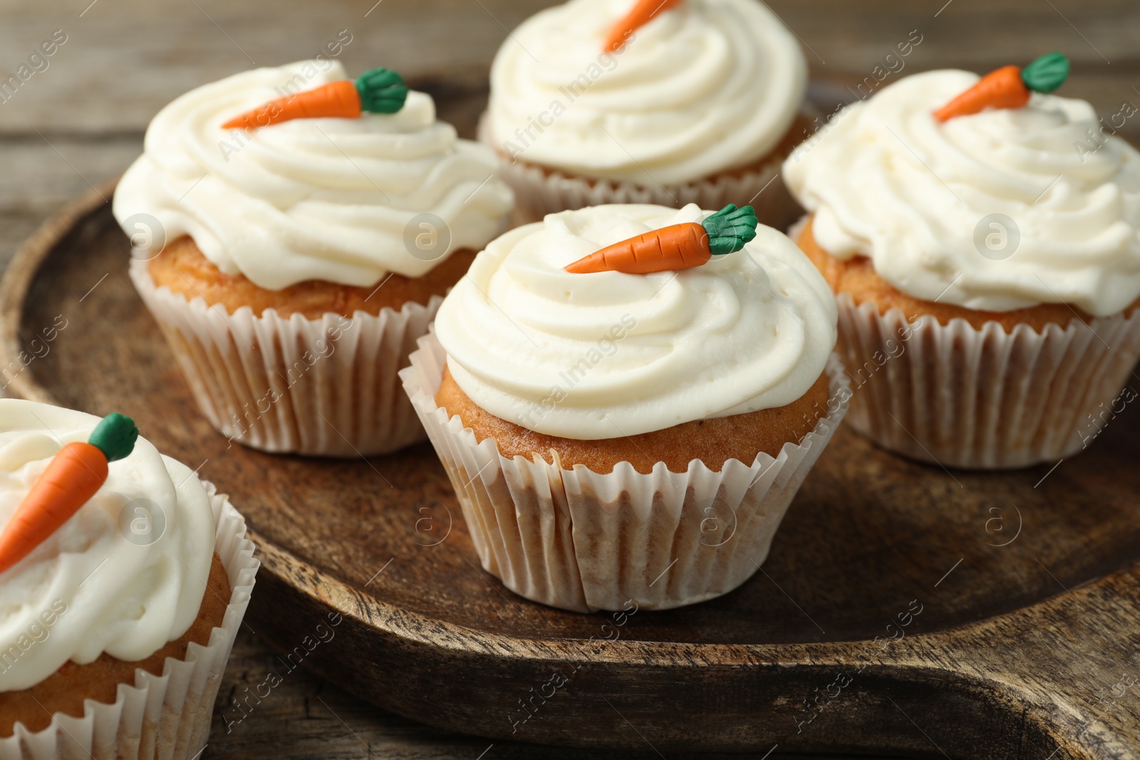 Photo of Delicious carrot cupcakes on wooden table, closeup