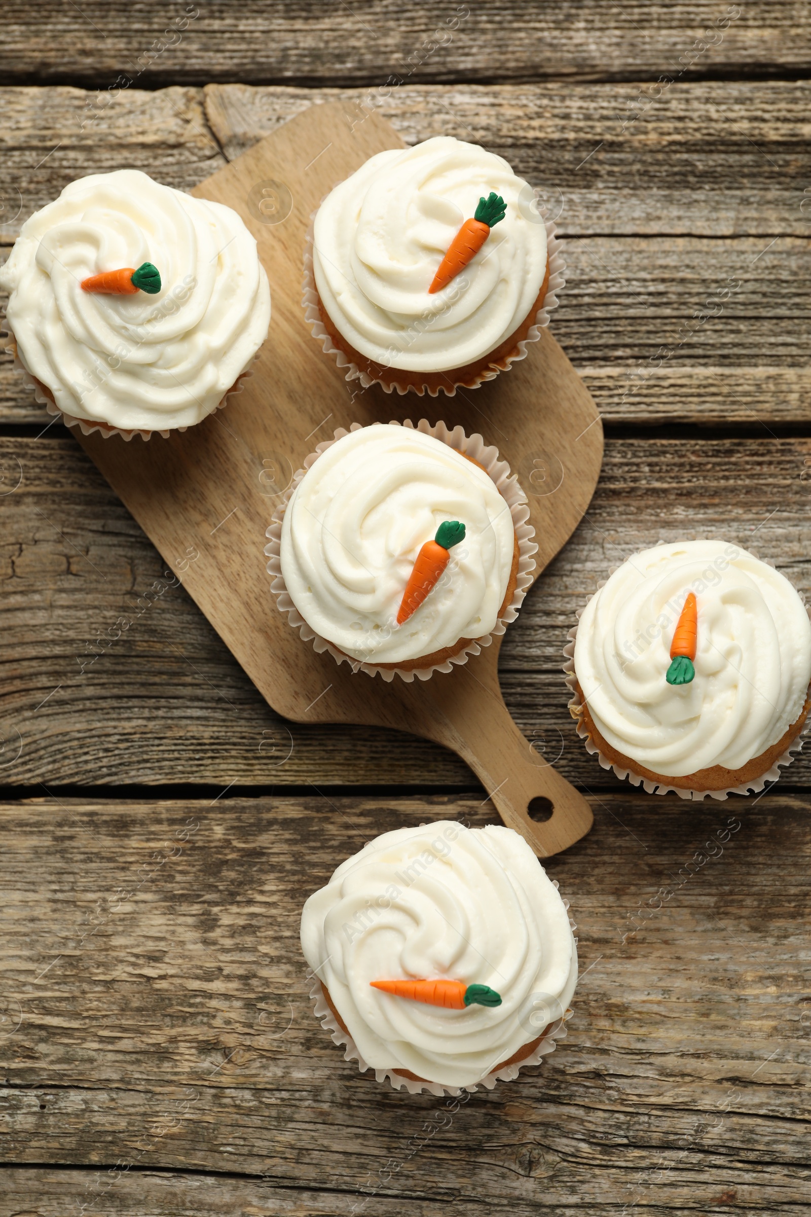 Photo of Delicious carrot cupcakes on wooden table, flat lay