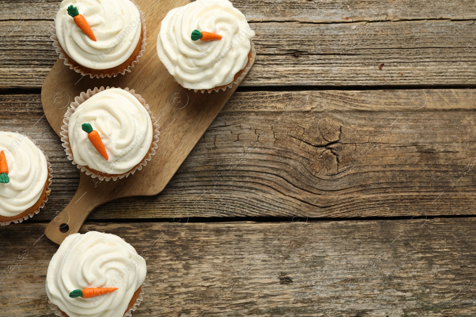 Photo of Delicious carrot cupcakes on wooden table, flat lay. Space for text