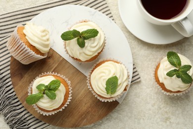 Photo of Delicious carrot cupcakes with mint and coffee on light textured table, flat lay