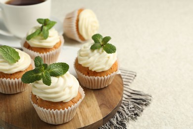 Photo of Delicious carrot cupcakes with mint on light textured table, closeup. Space for text