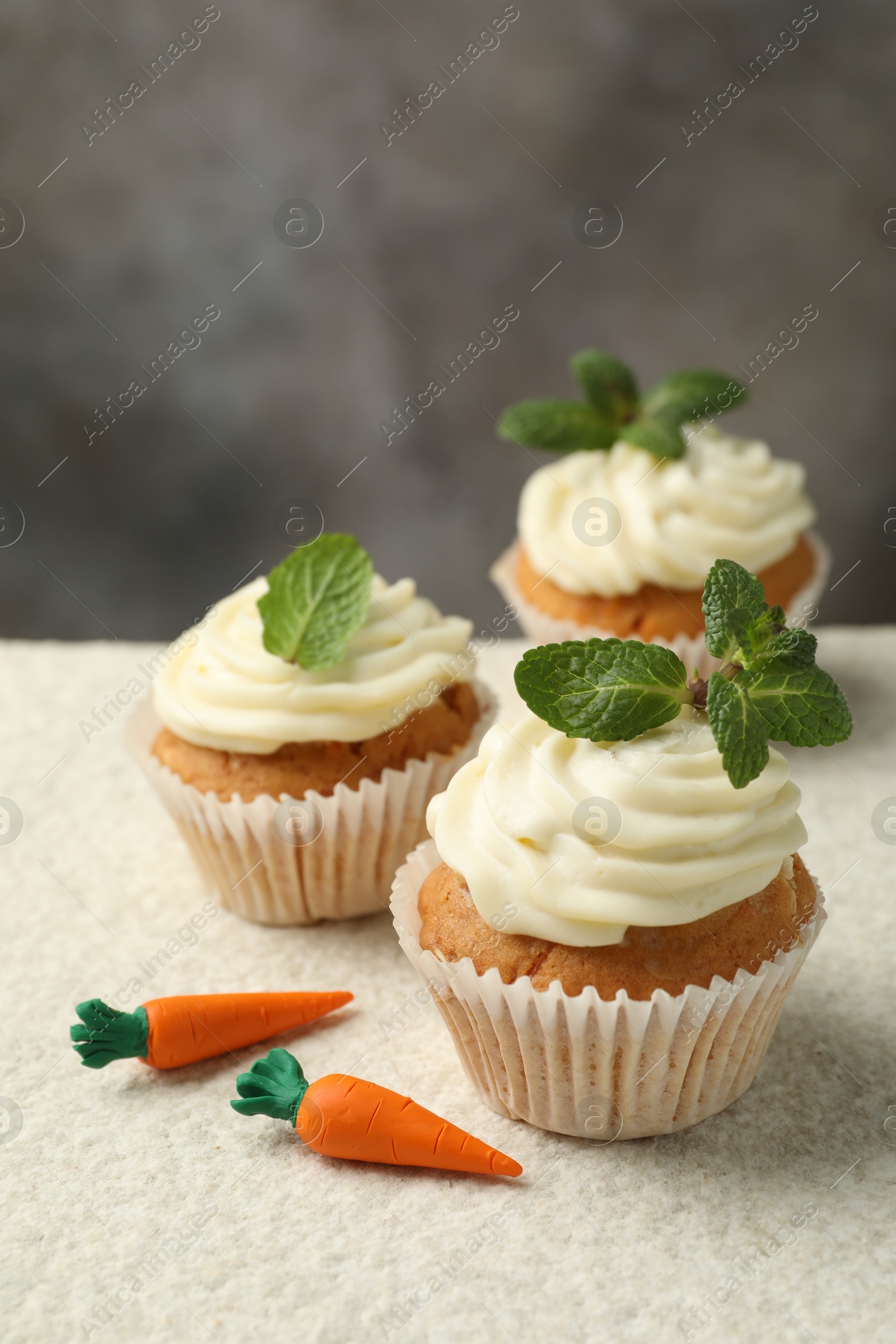 Photo of Delicious carrot cupcakes with mint on light textured table