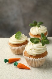 Photo of Delicious carrot cupcakes with mint on light textured table