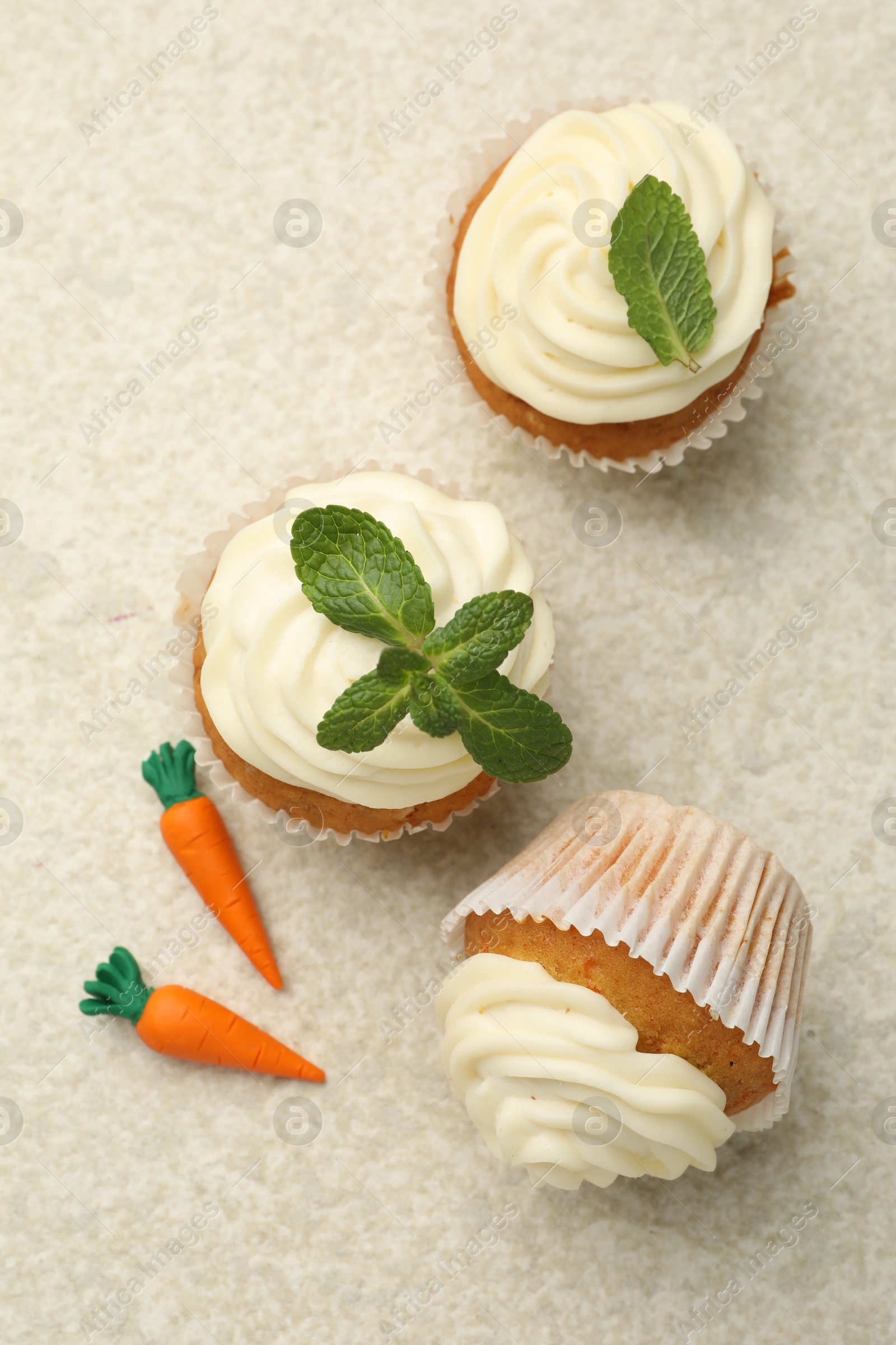 Photo of Delicious carrot cupcakes with mint on light textured table, flat lay