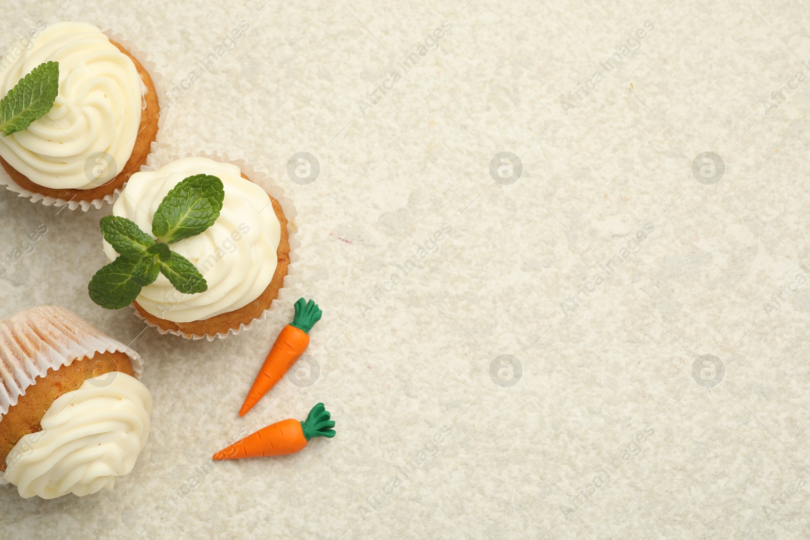 Photo of Delicious carrot cupcakes with mint on light textured table, flat lay. Space for text