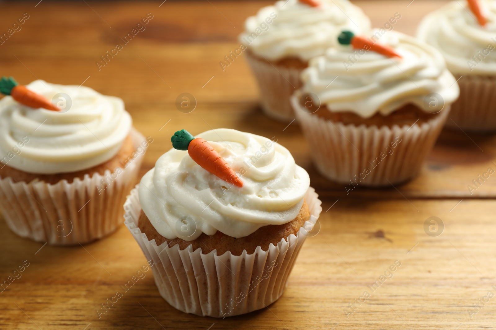 Photo of Delicious carrot cupcakes on wooden table, closeup