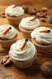 Photo of Delicious carrot cupcakes and walnuts on wooden table, closeup