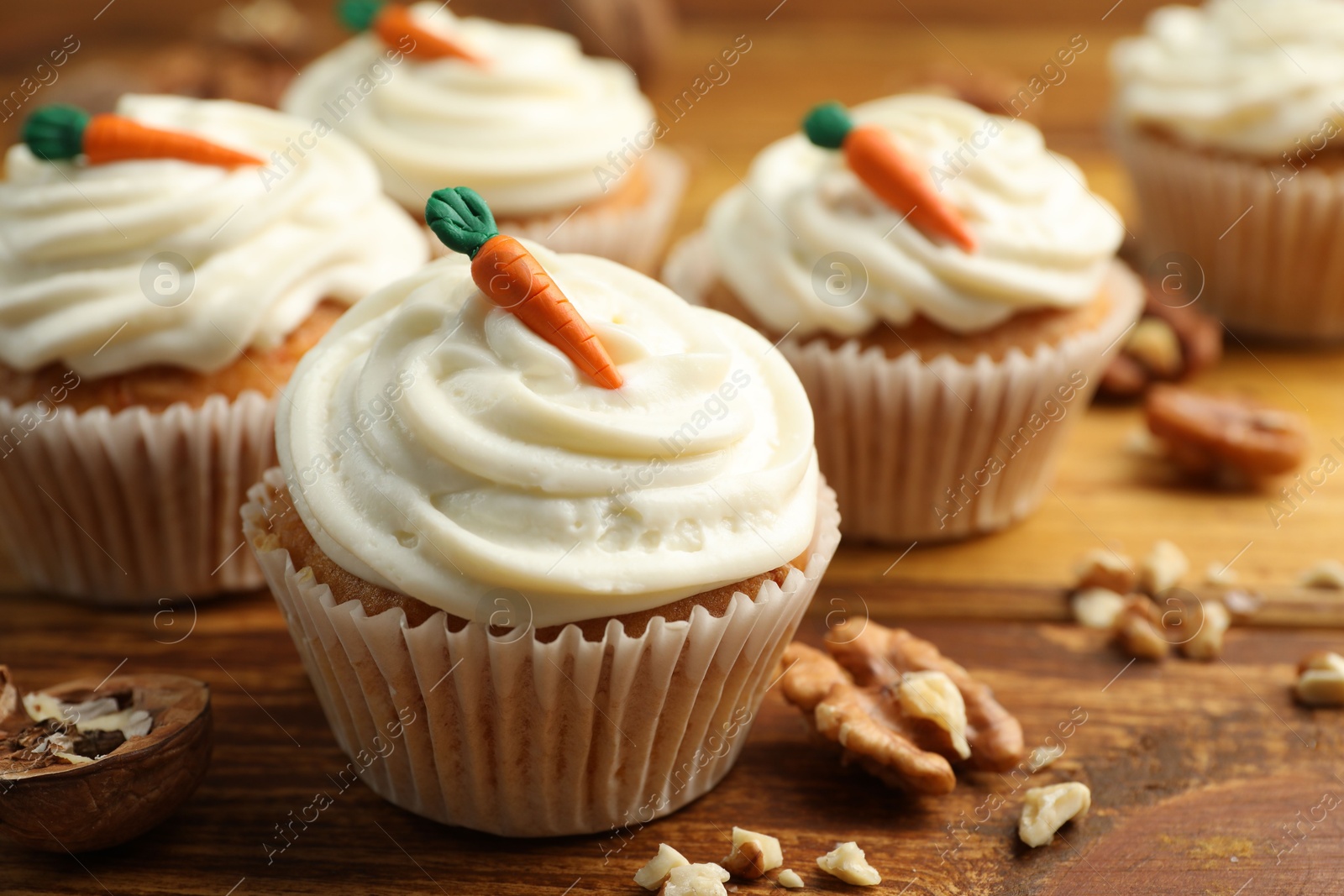 Photo of Delicious carrot cupcakes and walnuts on wooden table, closeup