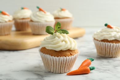 Photo of Delicious carrot cupcake with mint on white marble table, closeup