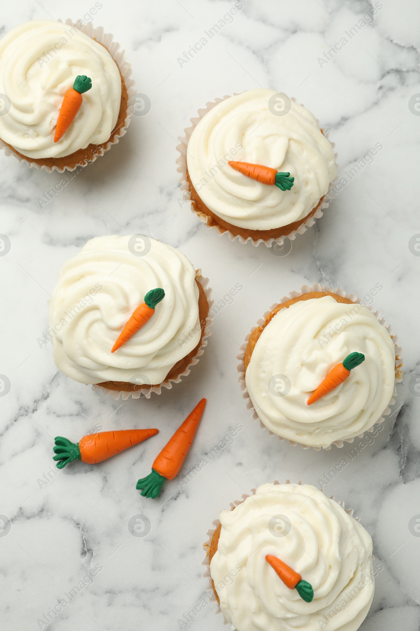 Photo of Delicious carrot cupcakes on white marble table, flat lay