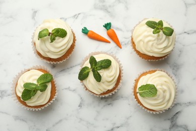 Photo of Delicious carrot cupcakes with mint on white marble table, flat lay