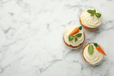 Photo of Delicious carrot cupcakes with mint on white marble table, flat lay. Space for text