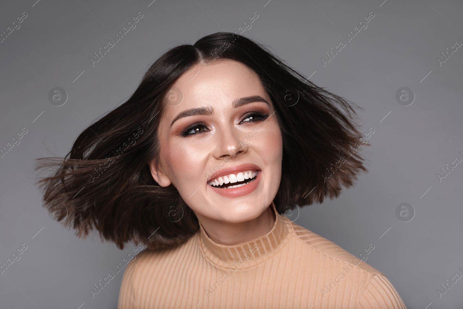 Photo of Portrait of beautiful young happy woman with gorgeous straight hair on grey background