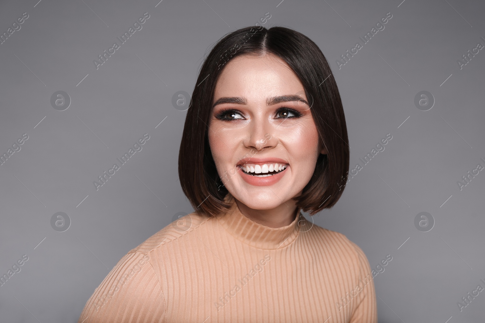 Photo of Portrait of beautiful young happy woman with gorgeous straight hair on grey background