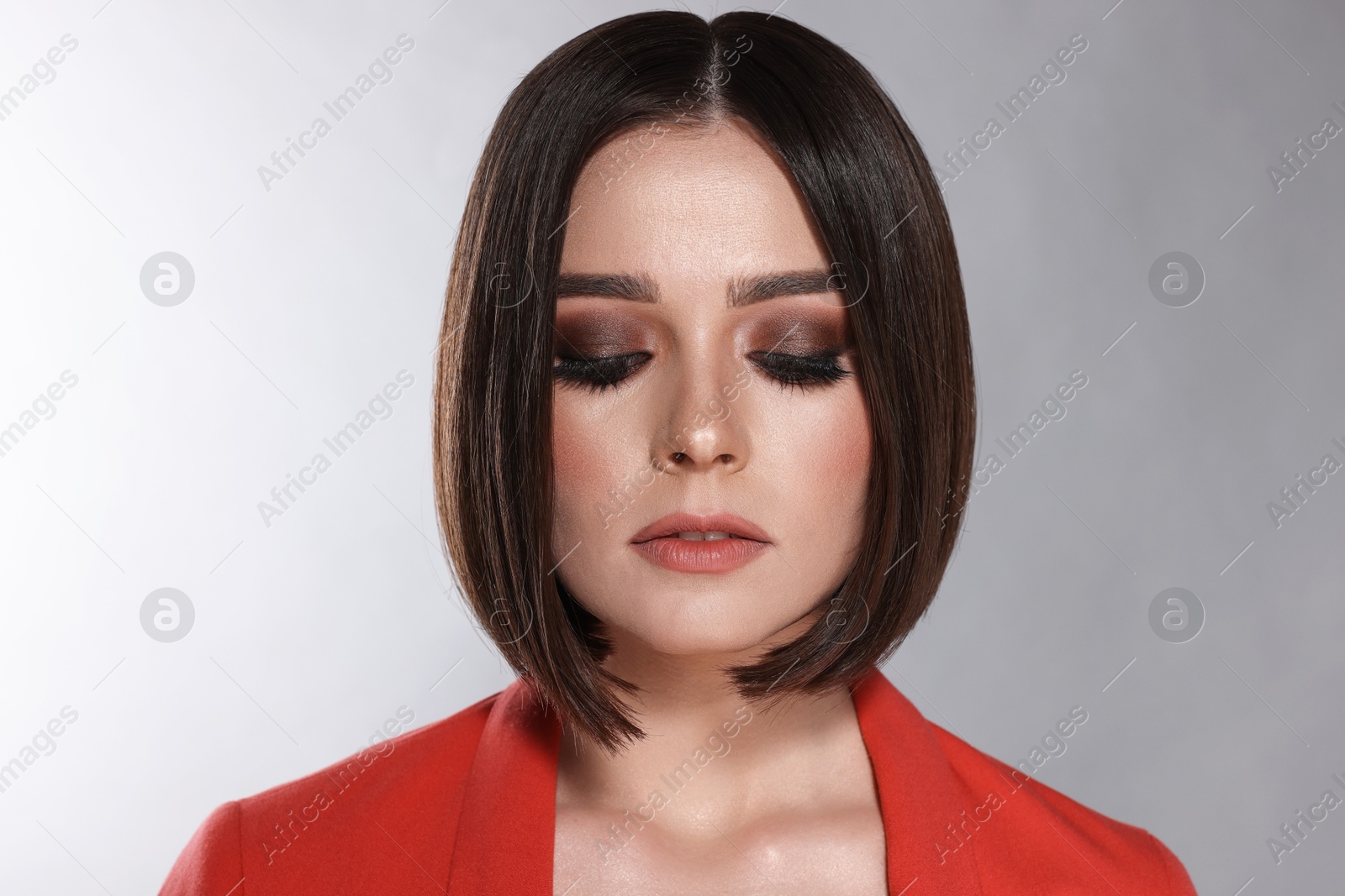 Photo of Portrait of beautiful young woman with gorgeous straight hair and stylish makeup on light grey background