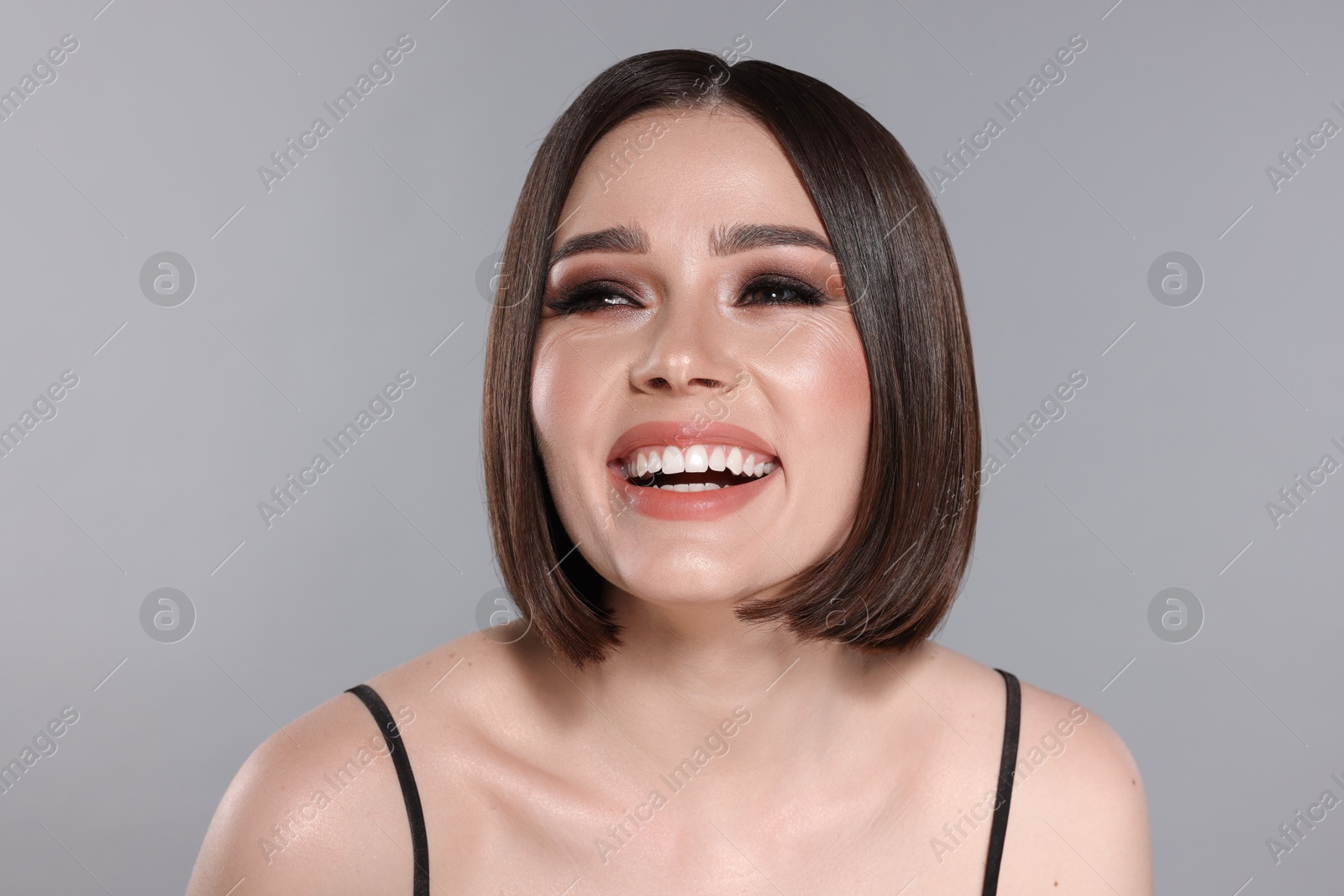 Photo of Portrait of beautiful young happy woman with gorgeous straight hair on light grey background