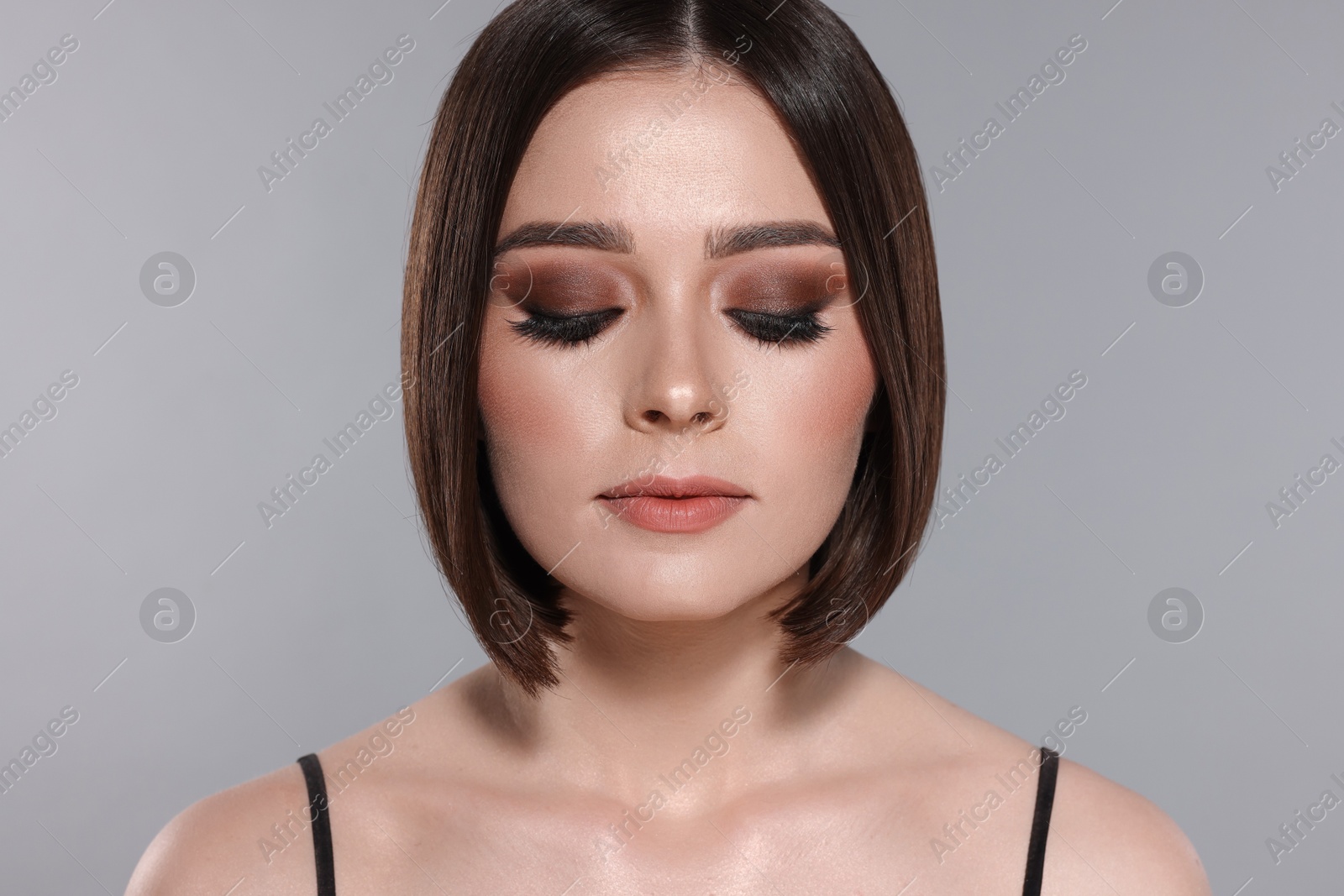 Photo of Portrait of beautiful young woman with gorgeous straight hair and stylish makeup on light grey background