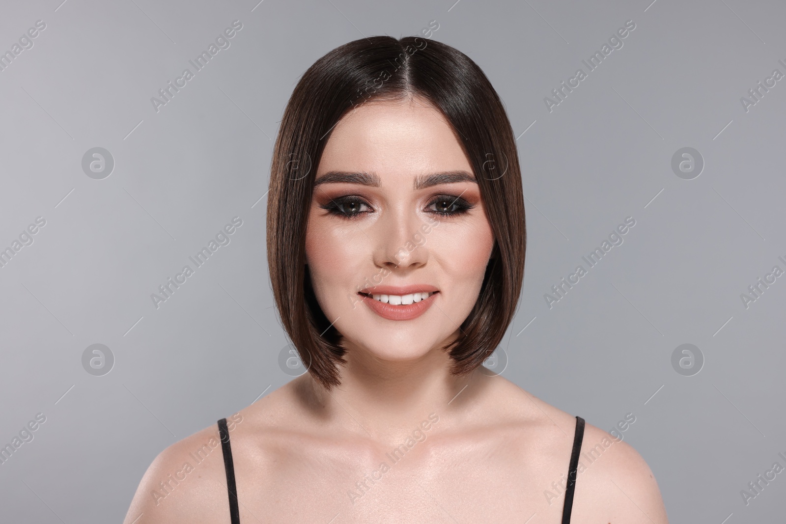 Photo of Portrait of beautiful young happy woman with gorgeous straight hair on light grey background