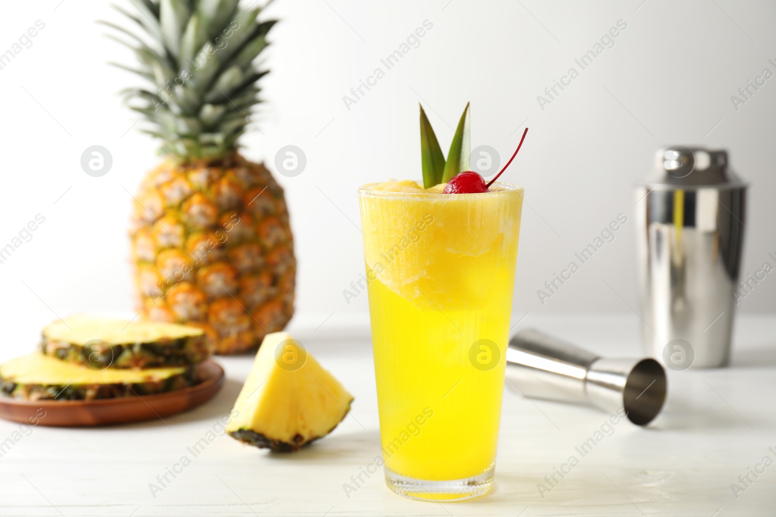 Photo of Tasty pineapple cocktail with cherry in glass on light table