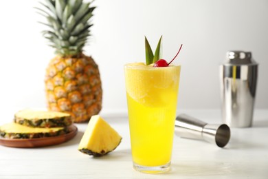 Photo of Tasty pineapple cocktail with cherry in glass on light table