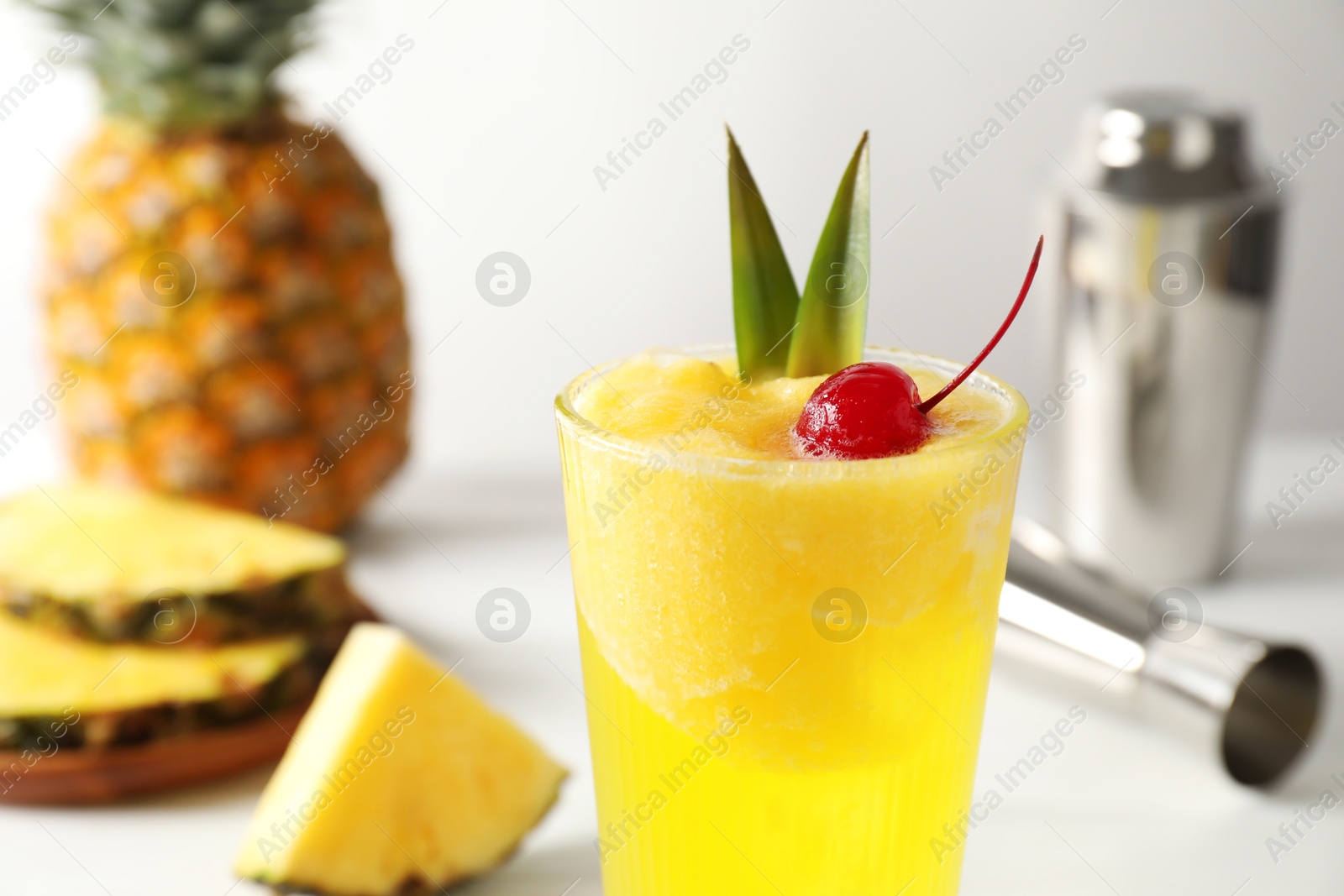 Photo of Tasty pineapple cocktail with cherry in glass on light table, closeup