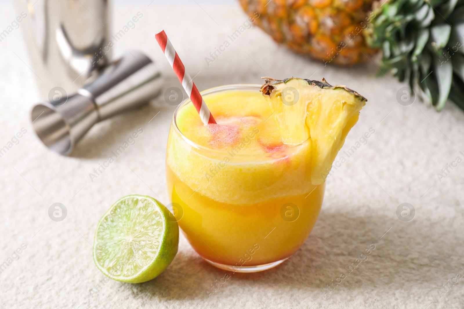 Photo of Tasty pineapple cocktail in glass served on white table, closeup