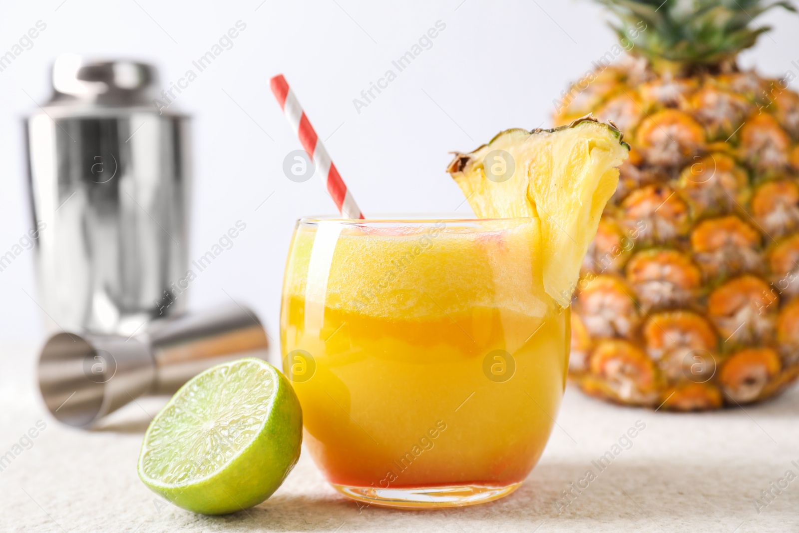 Photo of Tasty pineapple cocktail in glass served on white table, closeup