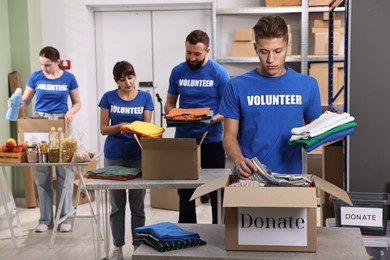 Group of volunteers packing donation goods at tables indoors