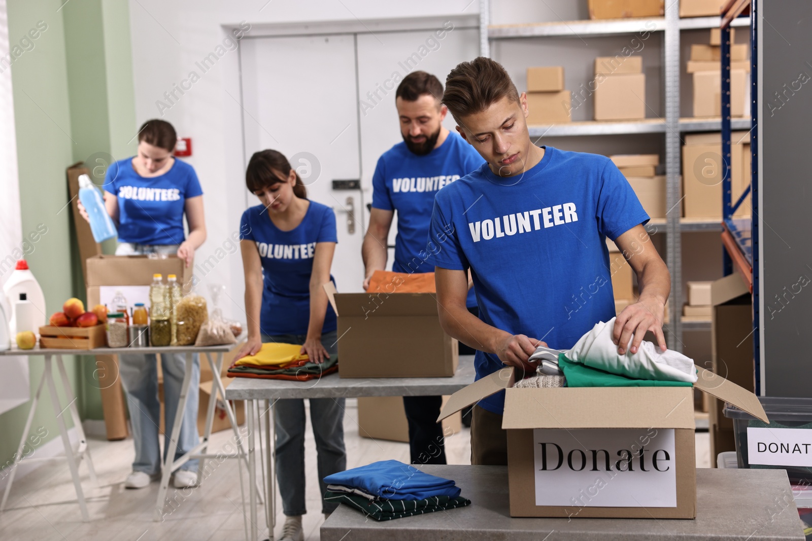 Photo of Group of volunteers packing donation goods at tables indoors