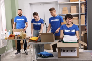 Group of volunteers packing donation goods at tables indoors