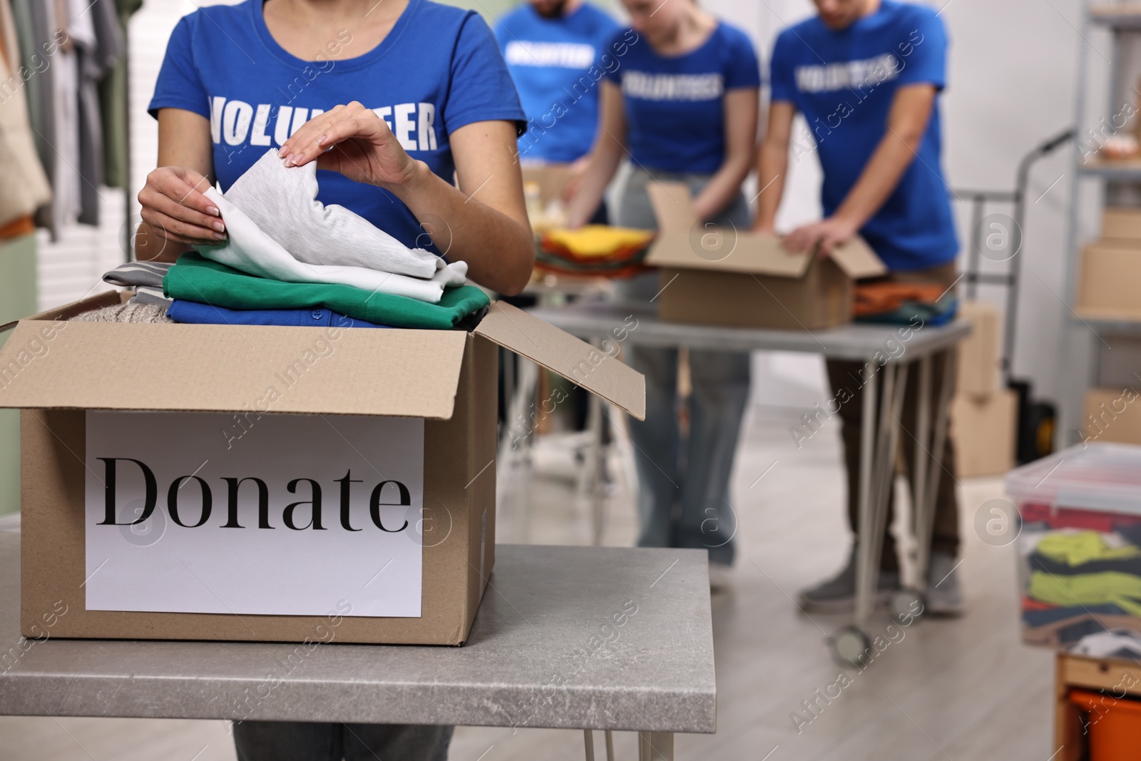 Photo of Group of volunteers packing donation goods at tables indoors, closeup