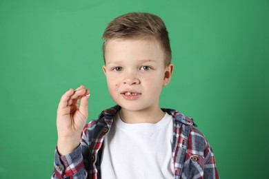 Photo of Cute little boy with missing tooth on green background. Waiting for tooth fairy